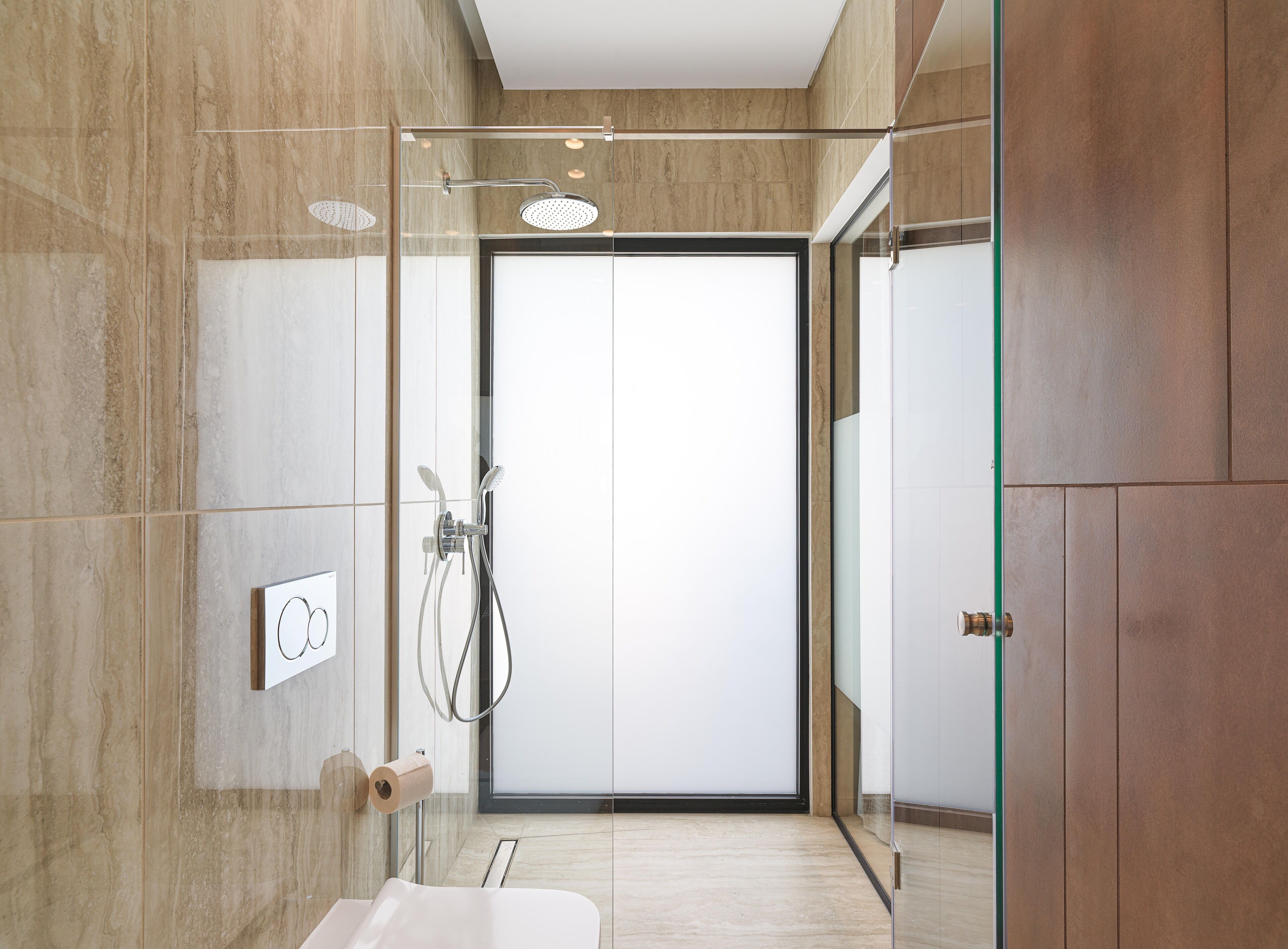 A modern bathroom with a glass shower enclosure, a toilet, and a sink.