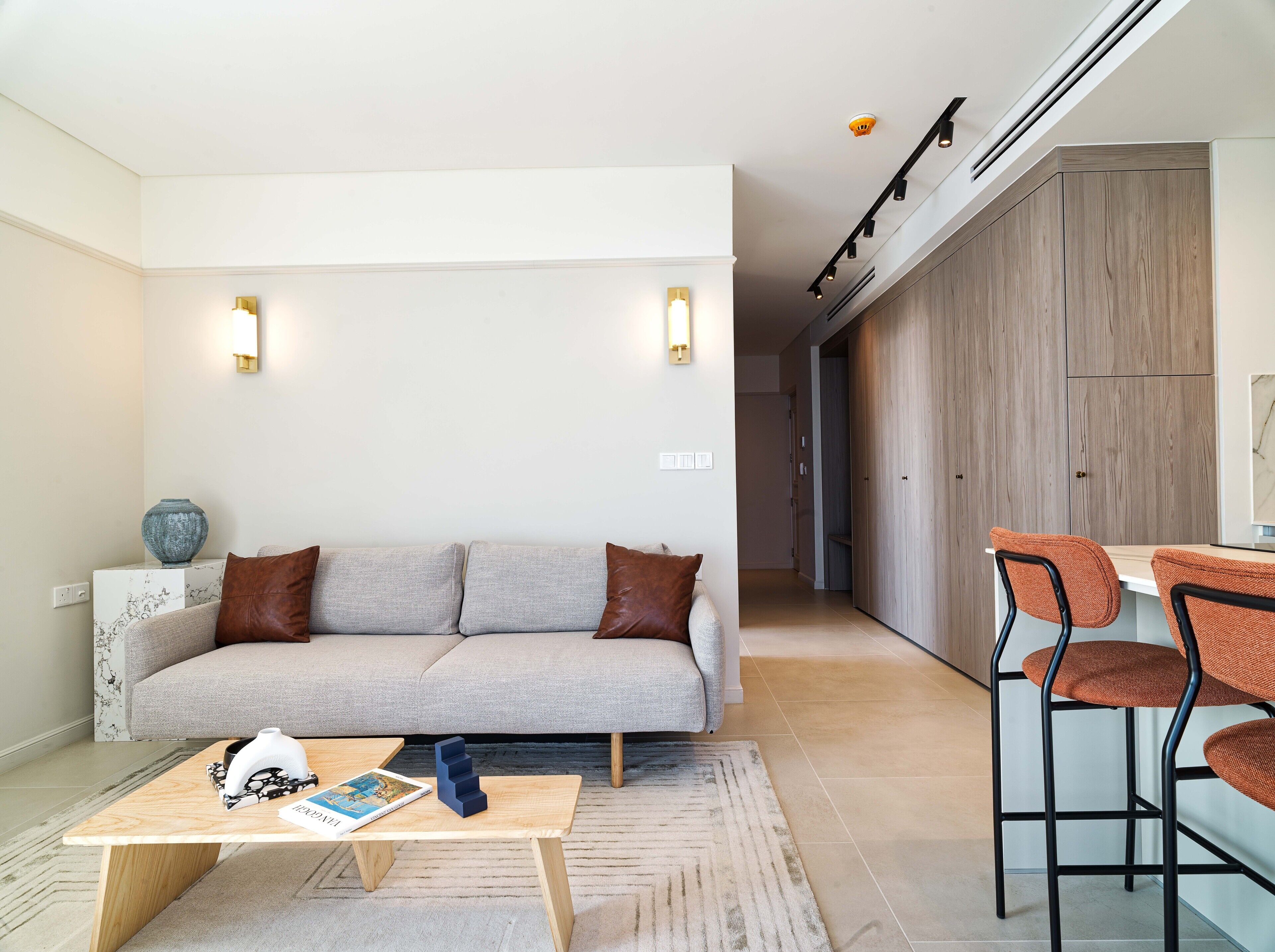 A modern living room with a sofa, coffee table, and two bar stools.