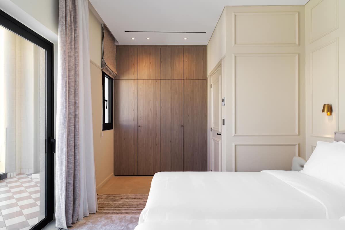 Un dormitorio con una cama grande, un armario, una puerta corredera y vistas a través de una ventana.
