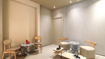Relax in a serene space with a large wall, two chairs, a round table, and a cushioned chair.