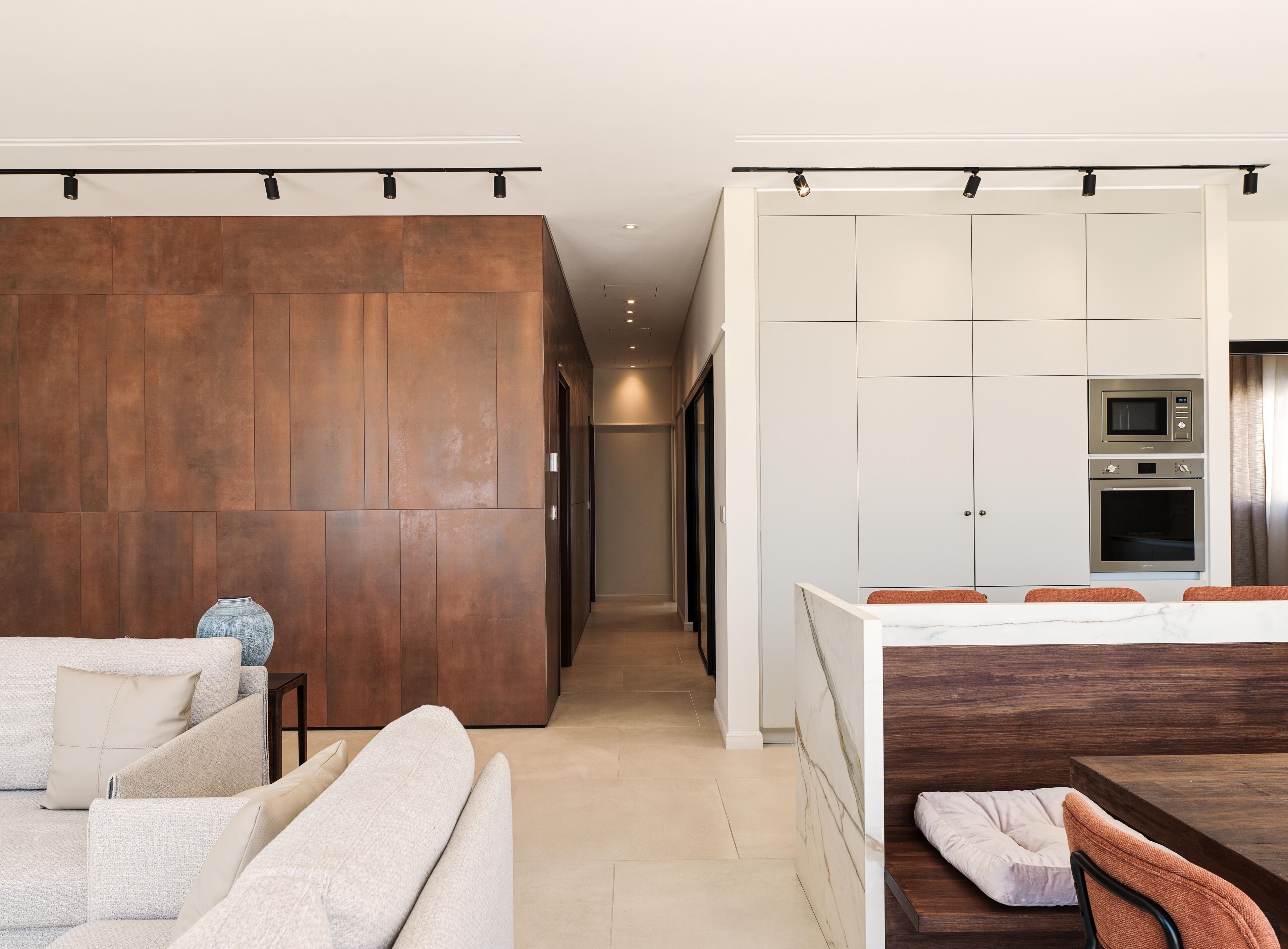 Una cocina moderna con electrodomésticos integrados, un comedor con mesa de madera y una sala de estar con un sofá grande.