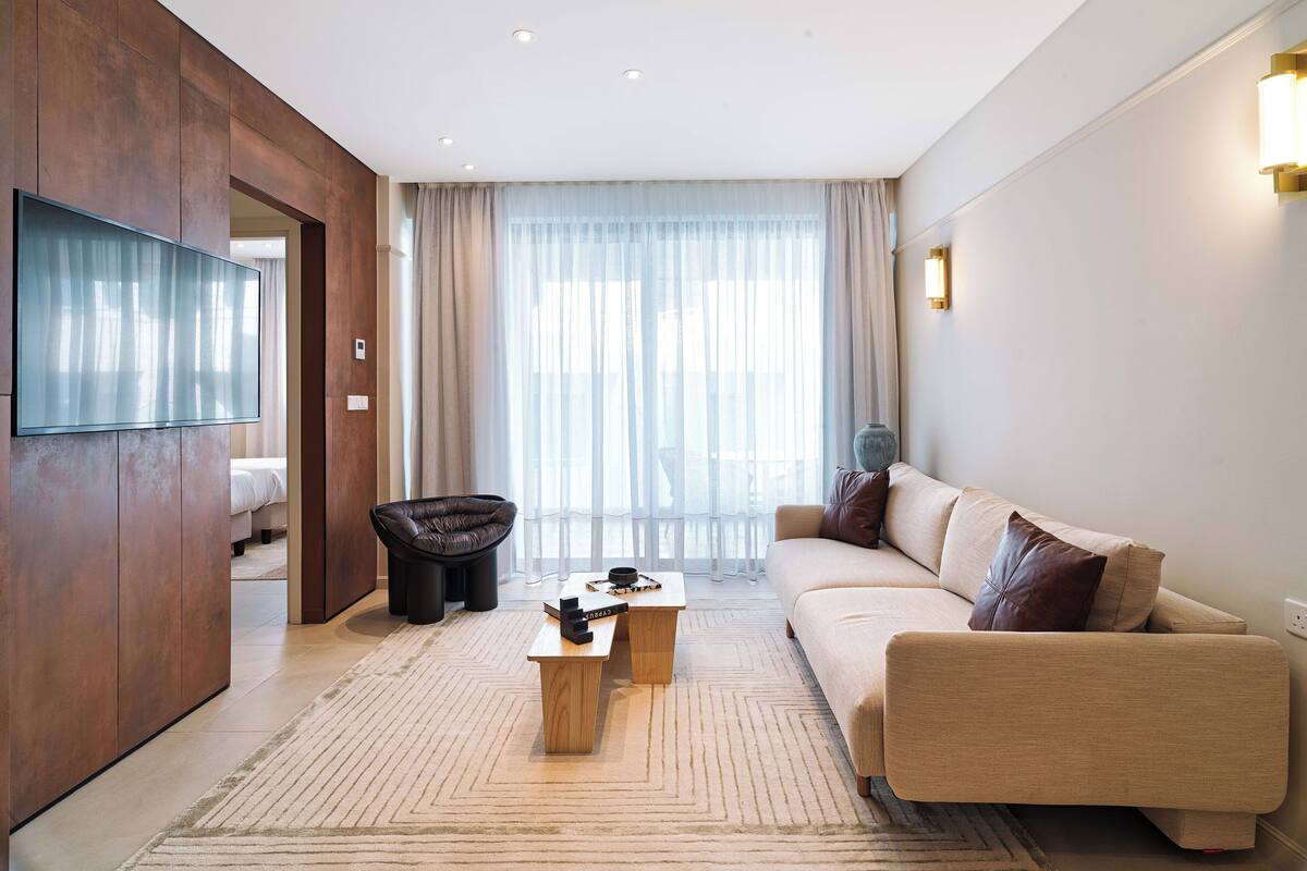 Una sala de estar moderna con una televisión de pantalla plana, un sofá, una silla y una mesa de centro.