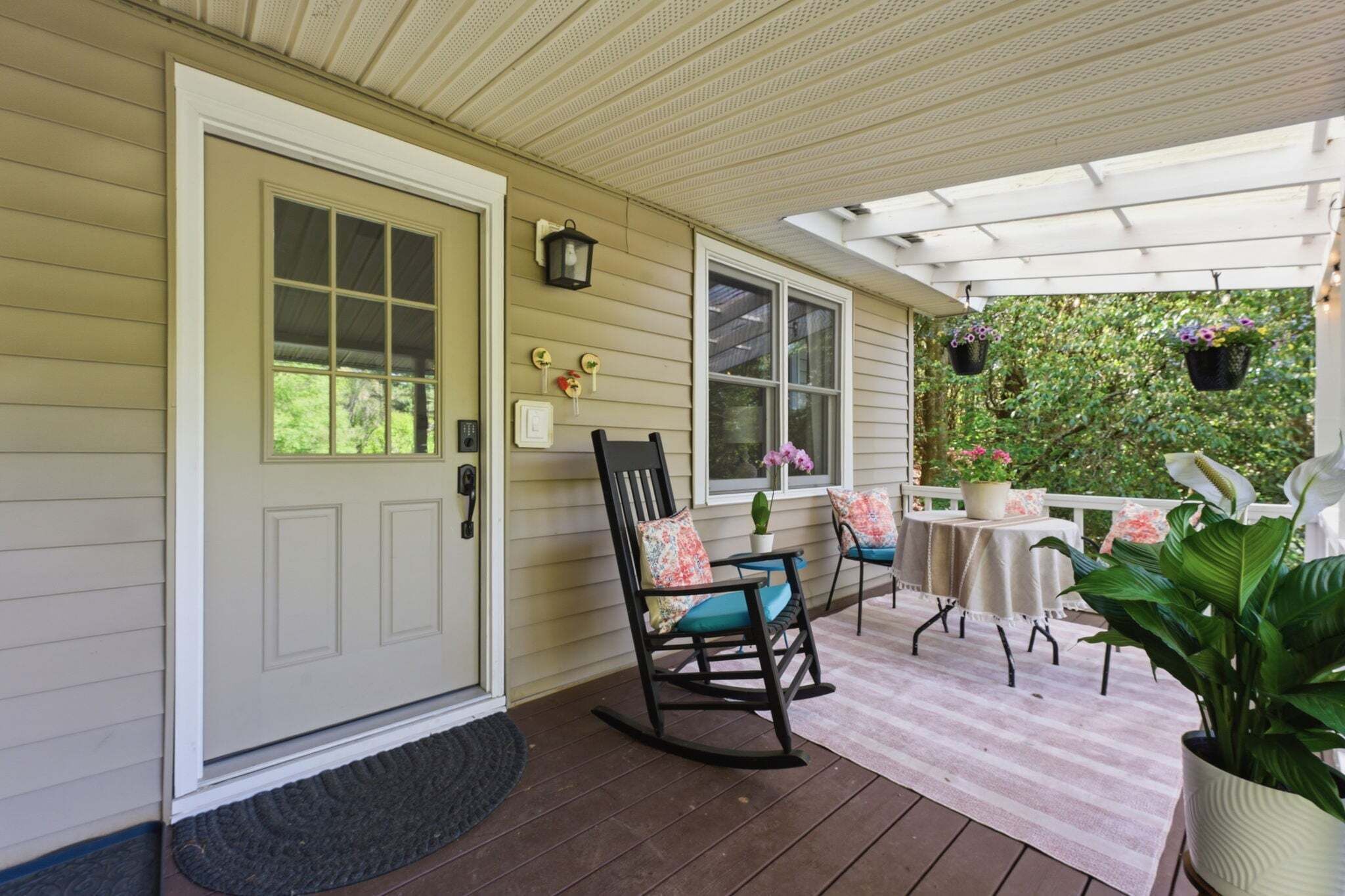 A porch with a rocking chair, a table, and hanging flower baskets.