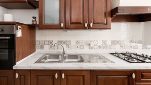 A kitchen with wooden cabinets, a stainless steel sink, a gas stove, and patterned backsplash tiles. - Spallanzani-San Camillo, apartment for 4 people (Roma)
