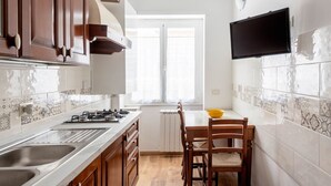 A kitchen with wooden cabinets, a gas stove, a sink, and a dining table with chairs. - Spallanzani-San Camillo, apartment for 4 people (Roma)