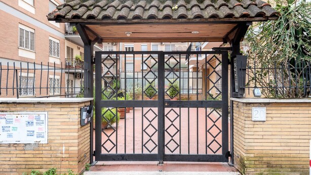 A gated entrance with a tiled roof, brick walls, and a metal gate. - Spallanzani-San Camillo, apartment for 4 people (Roma)