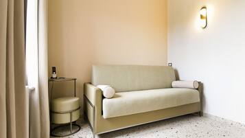 Una habitación minimalista con sofá, una mesita auxiliar y un aplique de pared.