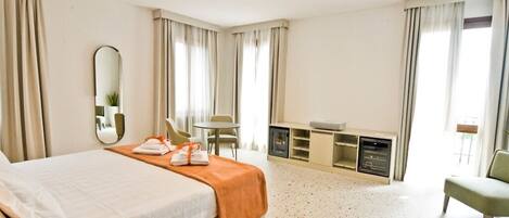 A hotel room with a bed, a desk, a chair, and a small table.