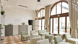 Um hall de hotel com balcão de recepção, área de estar e grandes janelas.