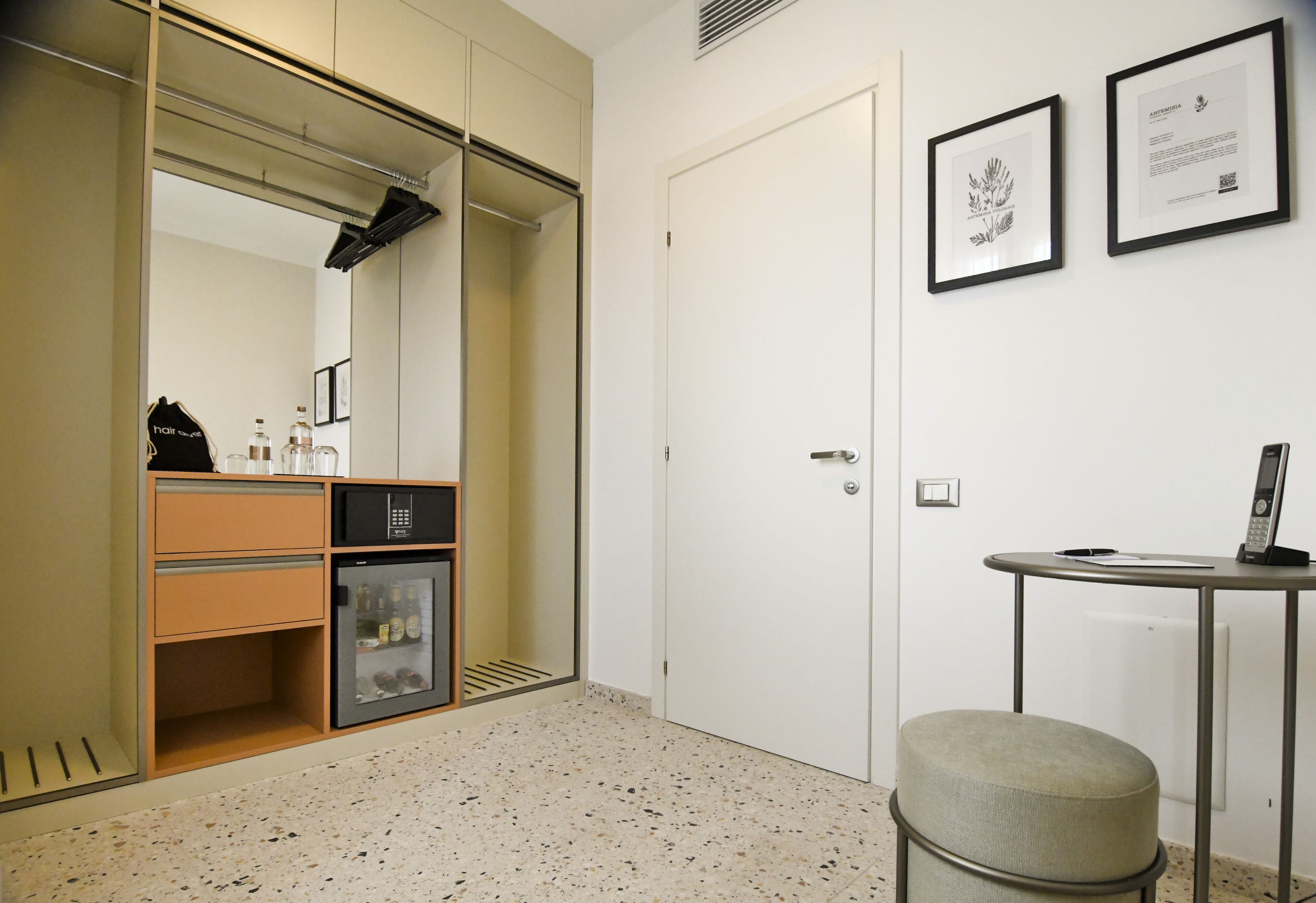 Habitación de hotel con armario, una mesita de noche y un espejo.