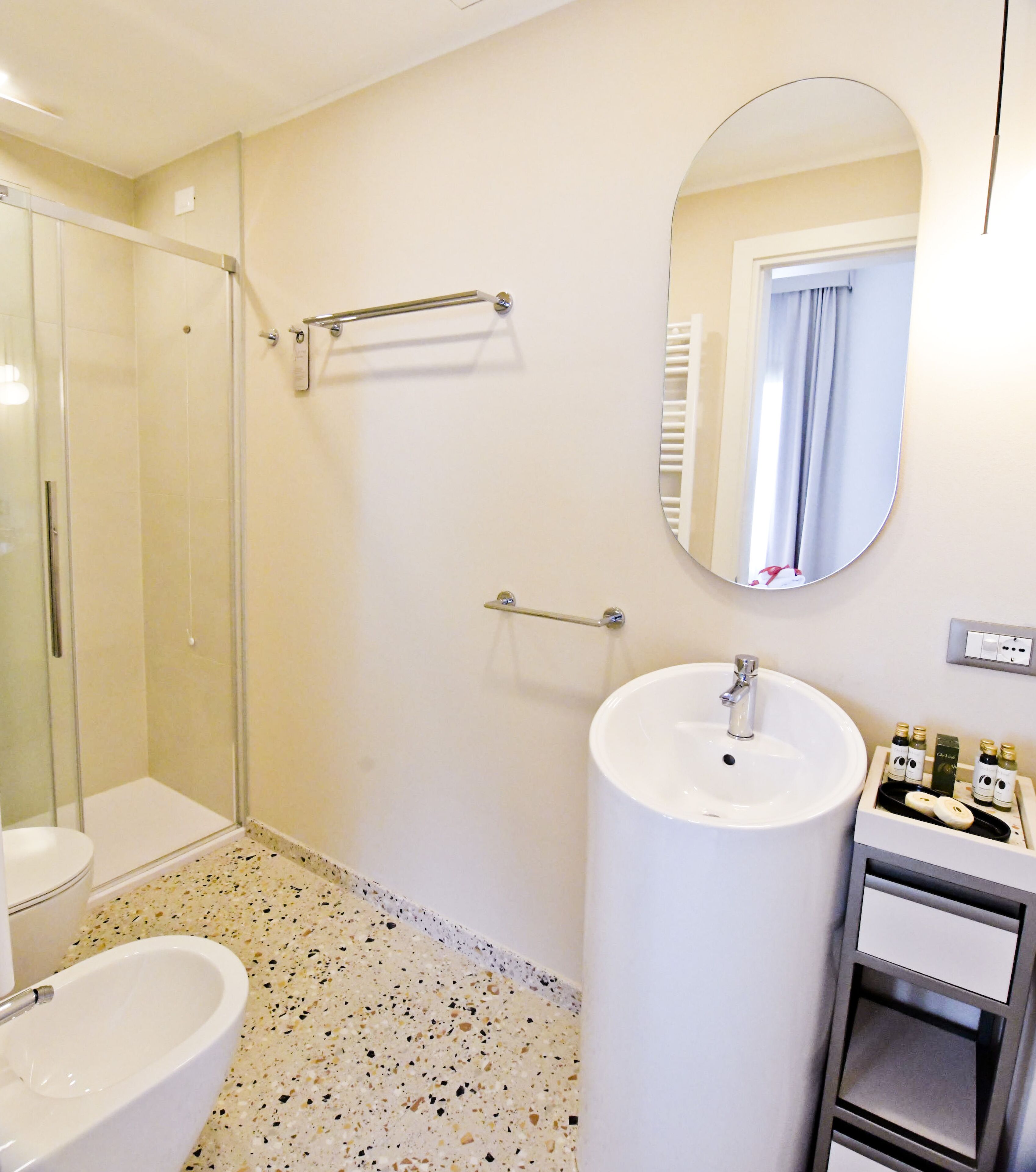 Une salle de bain avec une douche à parois de verre, des toilettes, un bidet, un lavabo avec un miroir et un porte-serviettes.