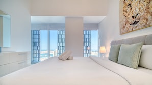 Een moderne slaapkamer met een groot bed, stadszicht en een luipaard afbeelding op de muur.