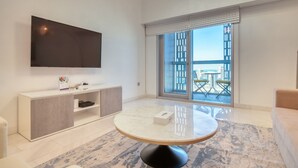 Een moderne woonkamer met een flatscreen-tv, een ronde salontafel, een bank en een balkon met uitzicht.