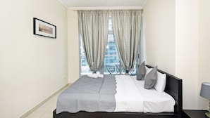 A modern bedroom with a bed, curtains, a framed picture, and a view of the city. - Cozy 1BR at Torch Tower Dubai Marina by Deluxe Holiday Homes (Dubai)
