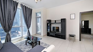 A modern living room with a sofa, TV stand, and a glass coffee table. - Cozy 1BR at Torch Tower Dubai Marina by Deluxe Holiday Homes (Dubai)