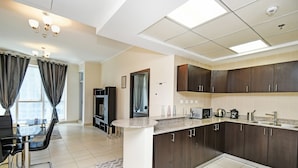 A modern kitchen with dark cabinets, a granite countertop, and a dining area with a table and chairs. - Cozy 1BR at Torch Tower Dubai Marina by Deluxe Holiday Homes (Dubai)