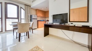 Een moderne woonkamer met een eethoek, een keuken met houten kastjes, een flatscreen televisie en een groot raam met gordijnen.