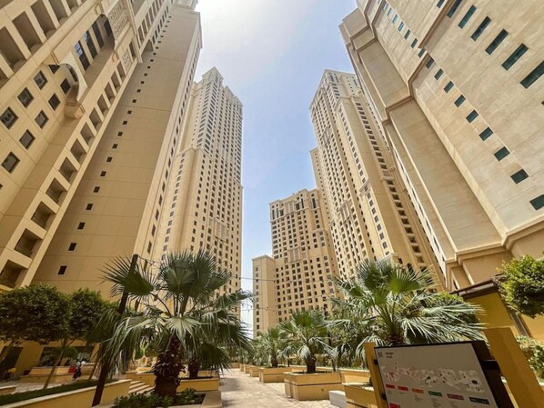 Vista de edificios residenciales altos con un patio central que tiene palmeras y un camino pavimentado.