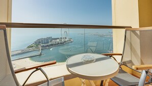Un balcón con mesa y sillas, con vista a un puerto deportivo con barcos y un puente.
