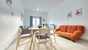Una sala de estar moderna con una mesa de comedor, dos sillas, un sofá y un ventanal con cortinas.