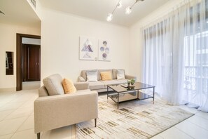 Uma sala de estar moderna com um sofá, uma mesa de centro e uma janela grande com cortinas leves.