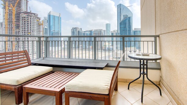 Un balcón con banco y mesa de madera, con vistas a la ciudad.