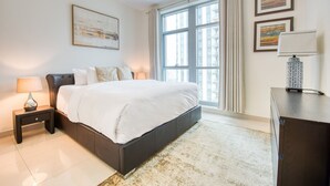 Un dormitorio moderno con una cama grande, una mesita de noche, una lámpara, un aparador y una ventana con cortinas.