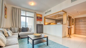 Una sala de estar moderna con un conjunto de sofá, una mesa de centro y vista a la cocina por un vano abierto.