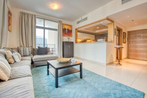 A modern living room with a sofa set, a coffee table, and a view of the kitchen through an open doorway.