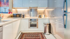 Una cocina moderna con armarios blancos, electrodomésticos de acero inoxidable y una alfombra estampada.