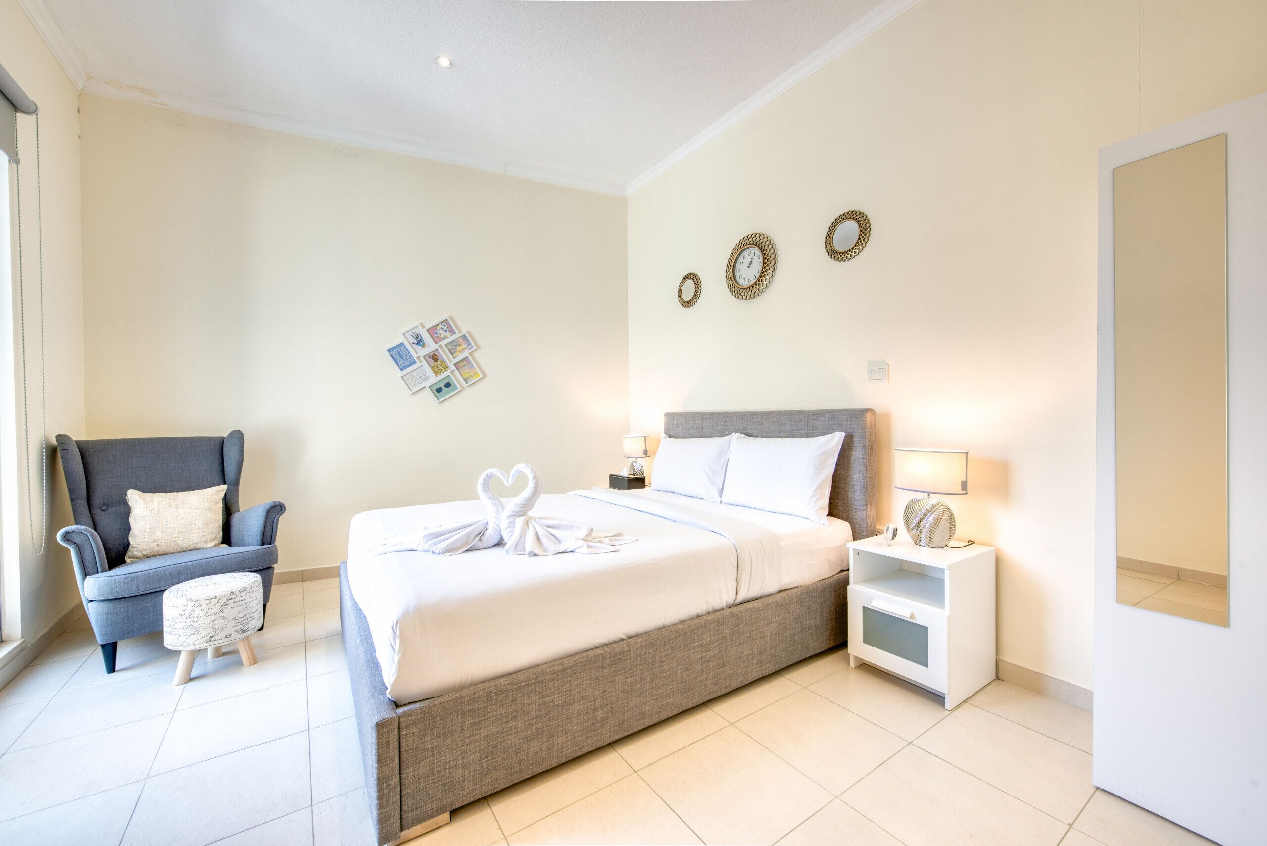 A bedroom with a bed, a chair, a nightstand, and a wall clock.