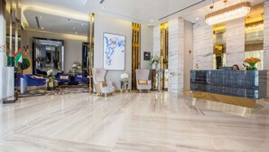 A modern lobby with a reception desk, seating area, and a large abstract painting. - Serene Canal Views from a Spacious Balcony, Just Steps from the Bus Stop (Dubai)