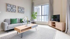A modern living room with a grey sofa, wooden coffee table, and a TV on a wooden stand. - Cozy 1BR at Bay Central 1 Dubai Marina by Deluxe Holiday Homes (Dubai)