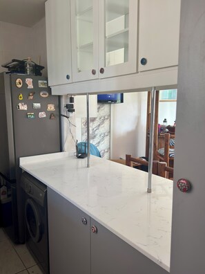 A kitchen with a marble countertop, a washing machine, and a refrigerator with magnets. - Family-friendly, sea and breaker view, 2 min from beach (Amanzimtoti)