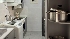 Une cuisine moderne avec des armoires blanches, un four encastré, un four à micro-ondes et un porte-ustensiles en acier inoxydable.