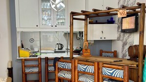 Une cuisine moderne avec des meubles blancs, une table à manger en bois et des chaises dotées de coussins à motifs.