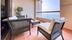 Ein Balkon mit Rattanmöbeln, einem Blumentopf und Blick aufs Meer.