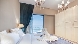 Ein Hotelzimmer mit einem großen Bett, Meerblick, einer Chandelier und einem Kleiderschrank.