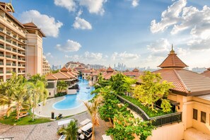 Um resort com piscina, palmeiras e vista para o horizonte da cidade.
