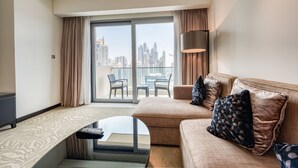 A modern hotel room with a sofa, a small table, and a view of the city skyline through large windows. - Graceful 1BR at The Address Residences Dubai Marina by Deluxe Holiday Homes (Dubai)