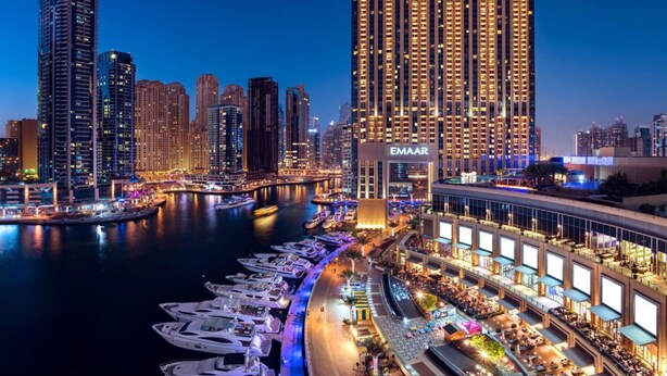 A high-rise building with "EMAAR" signage, a marina with yachts, and a waterfront dining area. - Graceful 1BR at The Address Residences Dubai Marina by Deluxe Holiday Homes (Dubai)