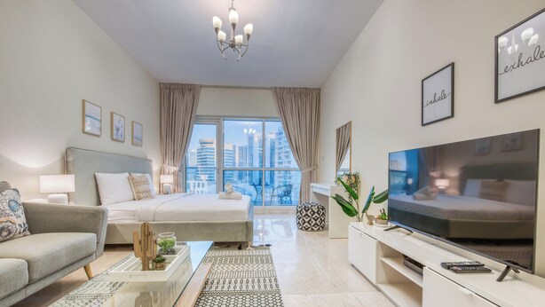 A modern hotel room with a bed, sofa, TV, and a balcony with a city view. - Prime Commercial Hub Near Burj Khalifa Studio Unit, Safeer Tower 1 (Dubai)