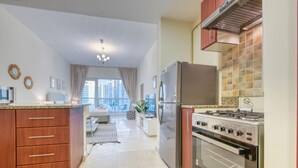 A modern kitchen with a refrigerator, stove, and microwave. - Prime Commercial Hub Near Burj Khalifa Studio Unit, Safeer Tower 1 (Dubai)