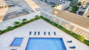 A rooftop pool area with multiple lounge chairs and two small pools. - Prime Commercial Hub Near Burj Khalifa Studio Unit, Safeer Tower 1 (Dubai)