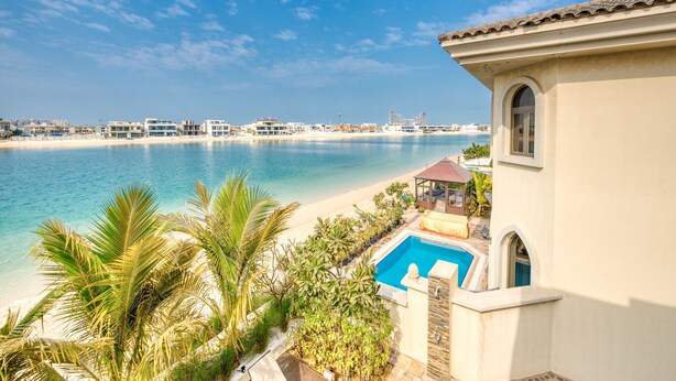 A beachfront property with a swimming pool, a covered patio, and a view of the ocean and distant buildings. - Immaculate 4BR Villa with Assistant Room and Private Pool at Frond O Palm Jumeirah by Deluxe Holiday Homes (Dubai)