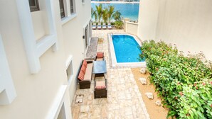 A pool area with a view of the sea, outdoor seating, and a small garden. - Immaculate 4BR Villa with Assistant Room and Private Pool at Frond O Palm Jumeirah by Deluxe Holiday Homes (Dubai)