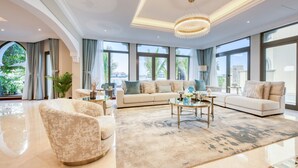A spacious living room with a large sofa set, a coffee table, and a chandelier. - Immaculate 4BR Villa with Assistant Room and Private Pool at Frond O Palm Jumeirah by Deluxe Holiday Homes (Dubai)