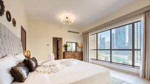 Habitación de hotel con una cama grande, vista del paisaje urbano y una lámpara de araña moderna.