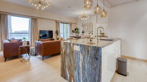 Una sala de estar moderna con una isla de mármol, sofás de cuero y un televisor de pantalla plana.