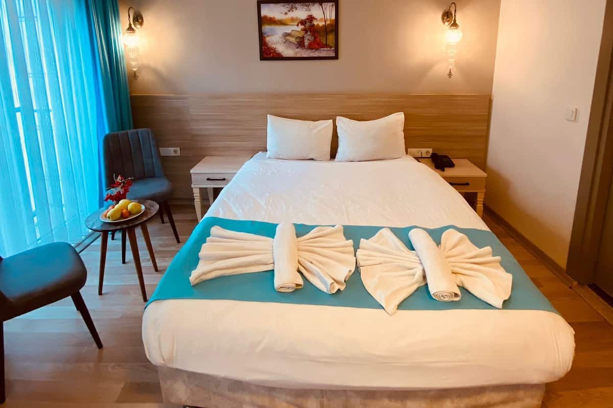 Ein Hotelzimmer mit einem großen Bett, einem Schreibtisch, einem Stuhl und einem Gemälde an der Wand.